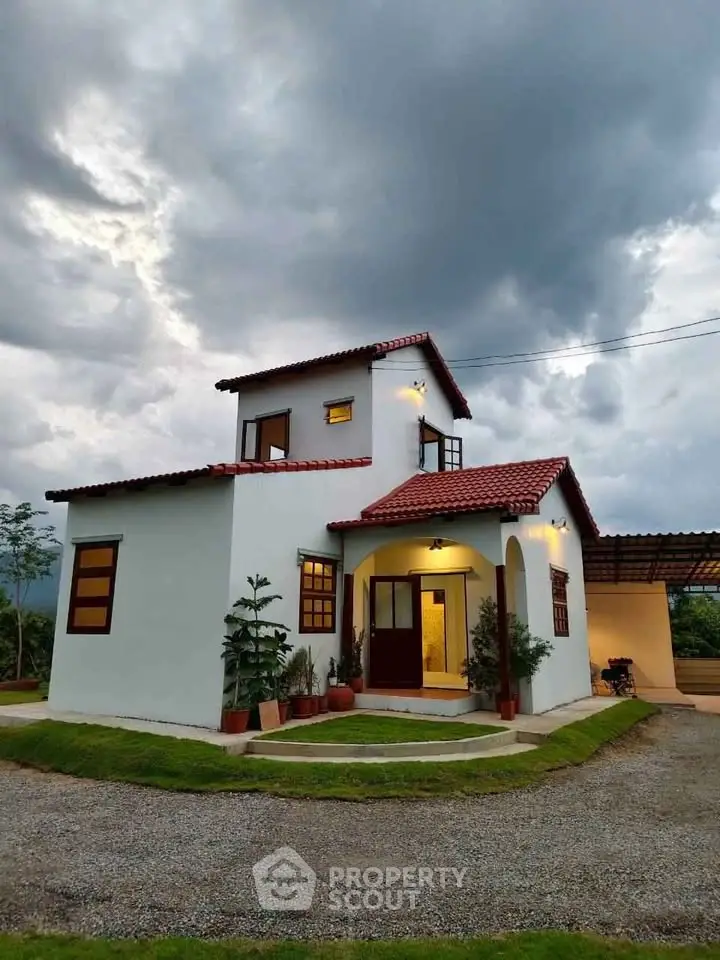 Charming two-story house with red roof and lush garden under dramatic cloudy sky.