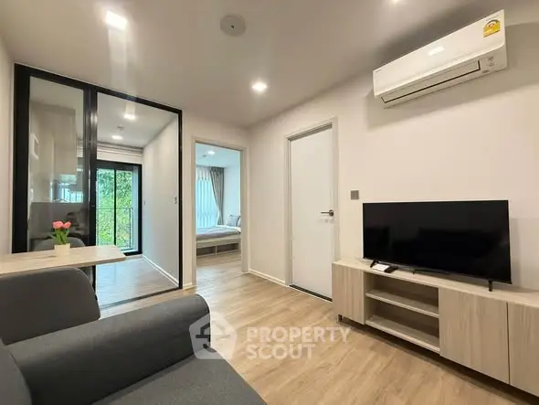 Modern living room with sleek design, featuring air conditioning and a view into the bedroom.