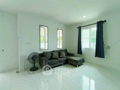 Bright living room with modern gray sofa and large windows, perfect for relaxation.