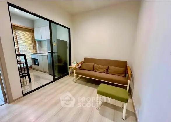 Cozy living room with modern kitchen view, featuring a comfortable sofa and stylish decor.