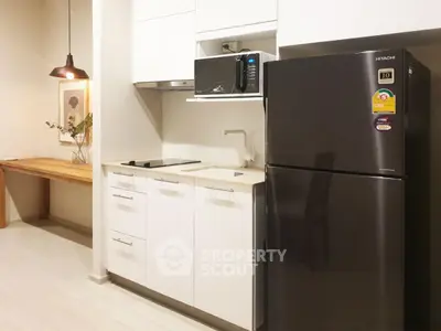 Modern kitchen with sleek white cabinets and black fridge, featuring a cozy dining nook.