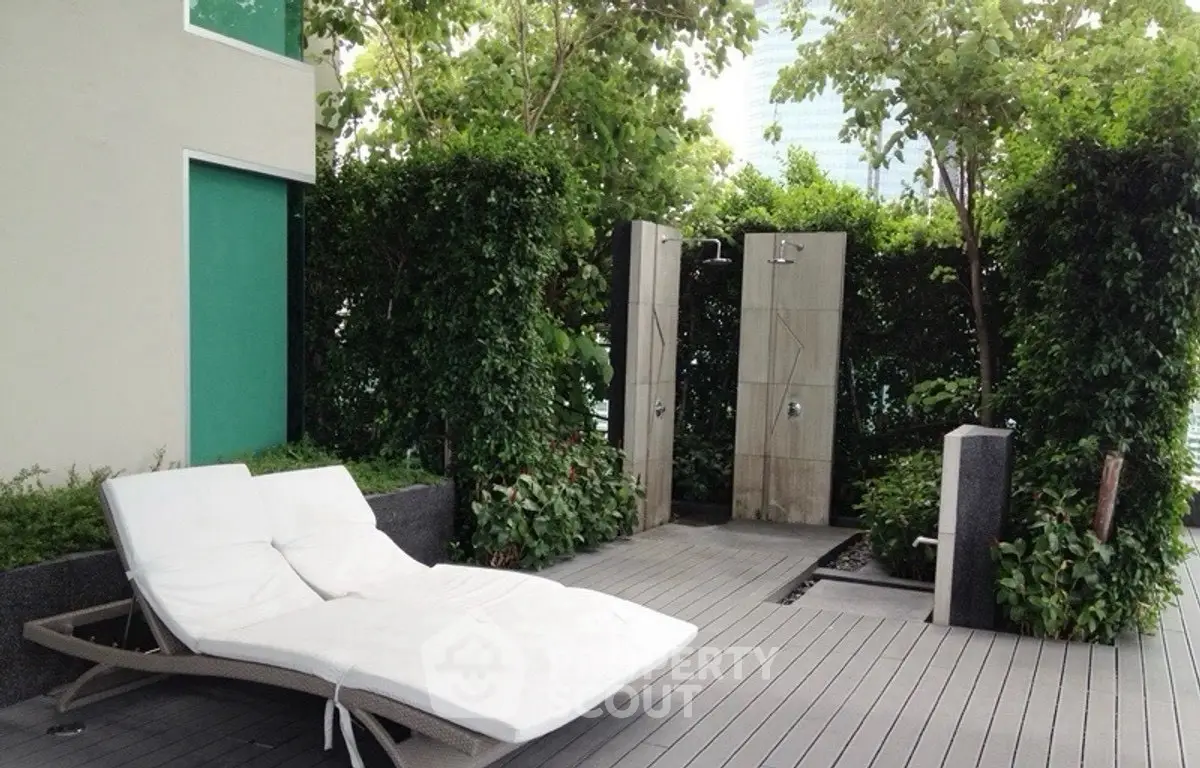 Luxurious garden area with outdoor showers and sun loungers, perfect for relaxation.