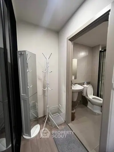 Modern bathroom with sleek fixtures and minimalist design, featuring a standing mirror and coat rack.