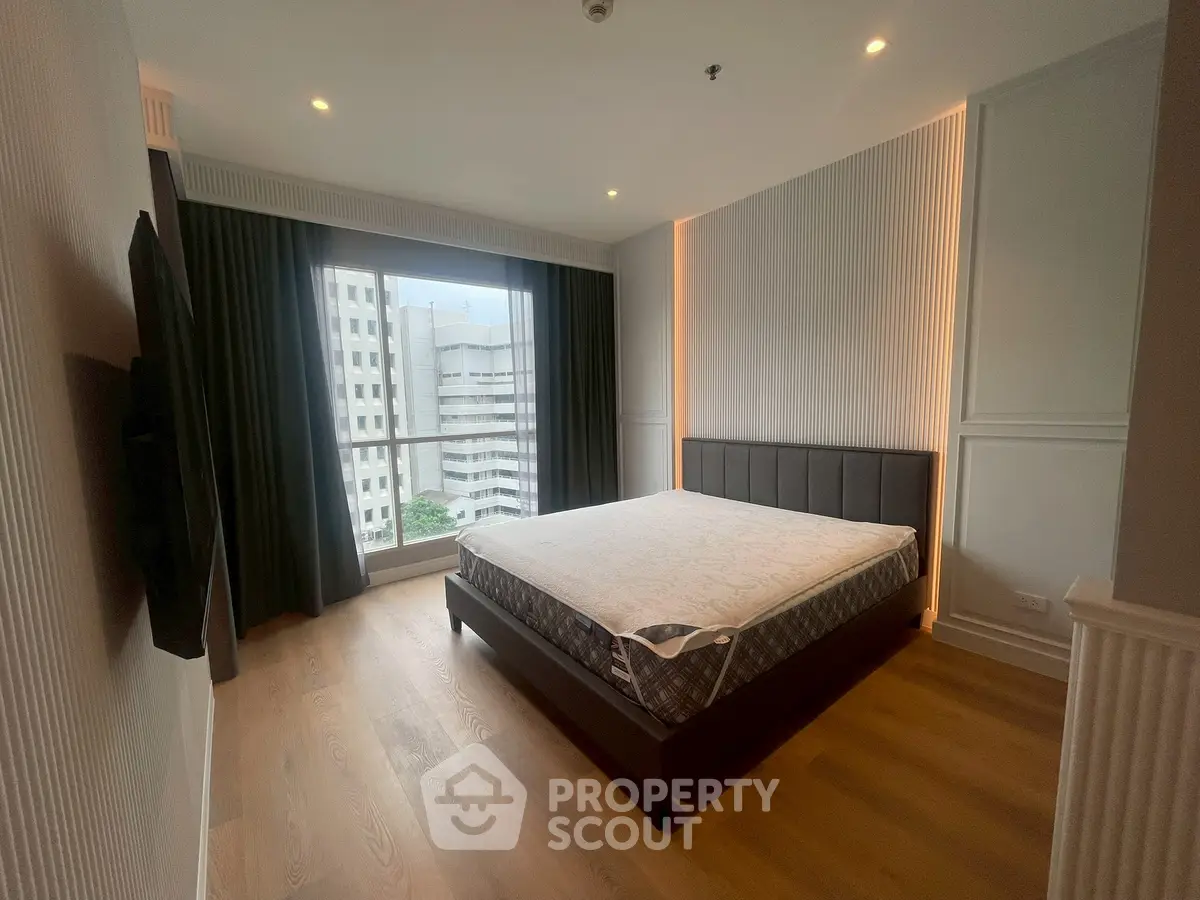 Spacious modern bedroom with large window and city view in a stylish apartment.
