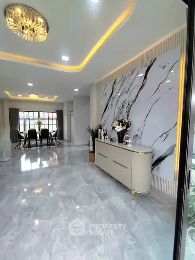 Luxurious open-plan living room with marble floors and elegant decor, featuring a modern chandelier and stylish dining area.