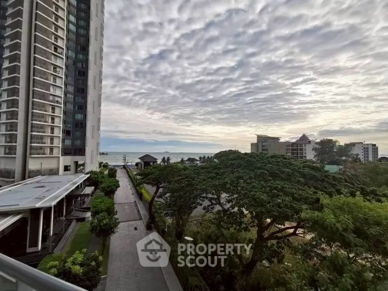 Stunning coastal view from high-rise building with lush greenery and ocean horizon.