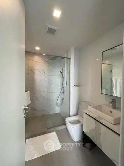 Modern bathroom with glass shower and sleek fixtures in a contemporary apartment.