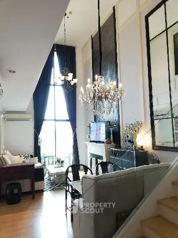 Luxurious living room with high ceilings, elegant chandelier, and large windows offering natural light.
