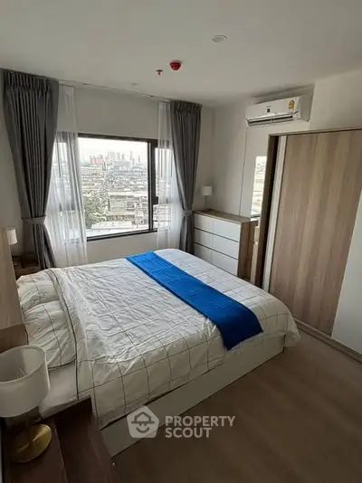 Modern bedroom with city view, featuring stylish decor and ample natural light.