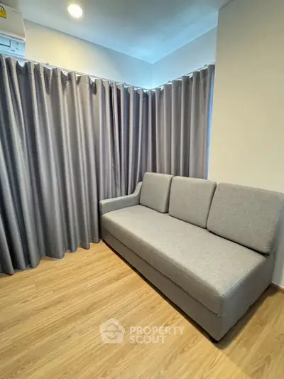 Cozy living room with modern gray sofa and elegant curtains, perfect for relaxation.