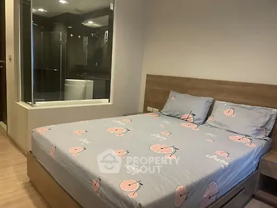Modern bedroom with glass wall view into sleek bathroom, featuring stylish decor and cozy ambiance.