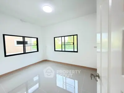 Bright empty room with large windows and glossy tiled floor in modern home.