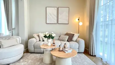 Elegant living room with cozy sofa, modern decor, and natural light from large windows.