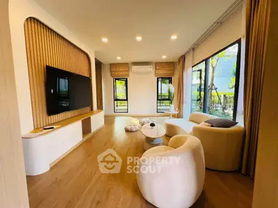 Modern living room with stylish furniture and large windows offering garden views.