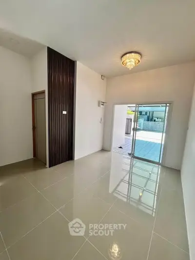 Spacious modern living room with elegant chandelier and sliding glass doors leading to a patio.