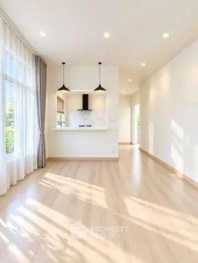 Bright and spacious living room with open kitchen layout and large windows.