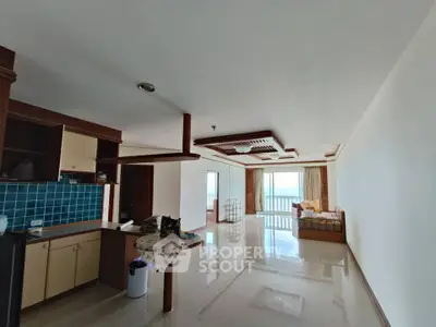 Spacious open-plan living room with ocean view and modern kitchen in luxury apartment.