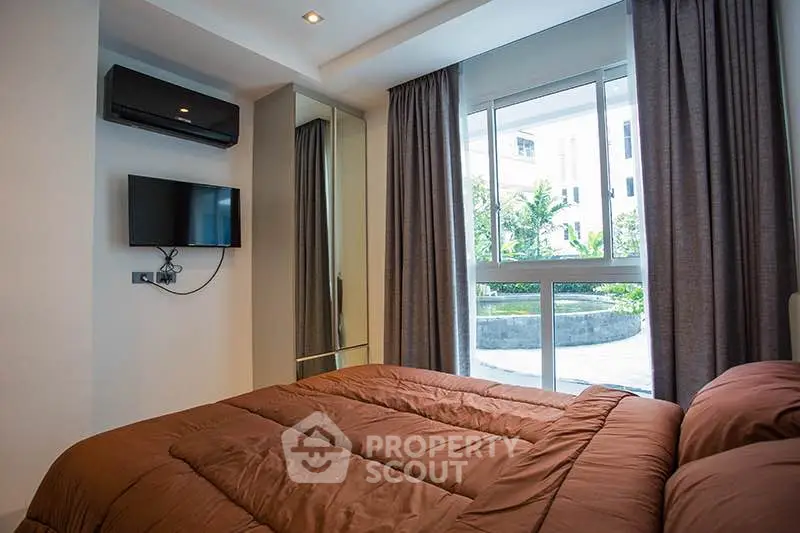 Cozy bedroom with modern decor and large window overlooking garden view.
