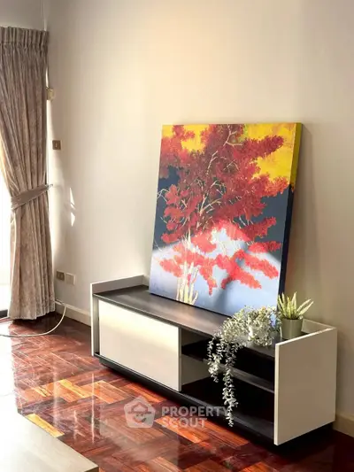 Stylish living room with elegant decor and vibrant artwork on wooden flooring.