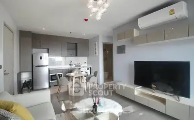 Modern living room with open kitchen, stylish decor, and large TV setup.