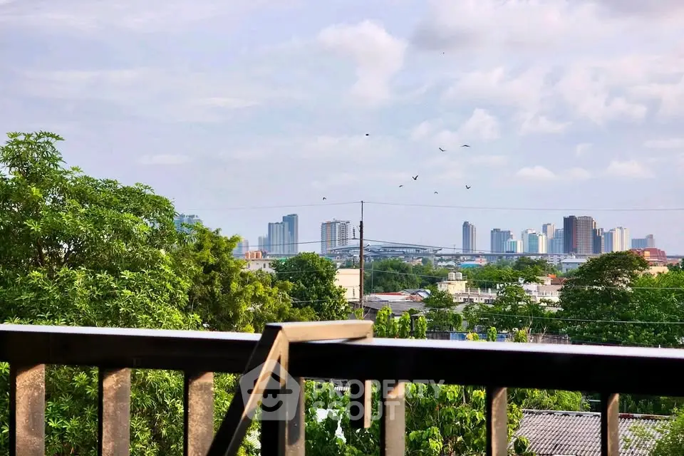 Stunning cityscape view from a balcony with lush greenery and skyline in the background.