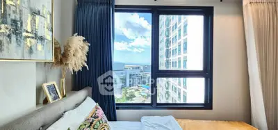 Modern bedroom with stunning city view from large window, elegant decor and cozy ambiance.