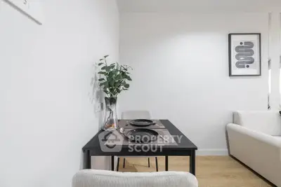 Modern dining area with sleek black table and minimalist decor in a bright apartment.