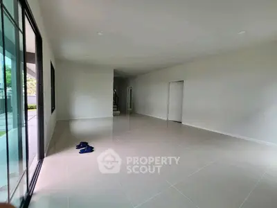 Spacious empty living room with large windows and tiled flooring, perfect for customization.