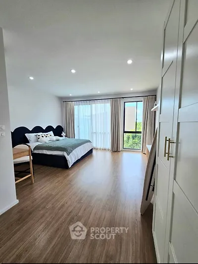 Spacious bedroom with modern decor and large window offering natural light and serene views.