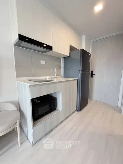 Modern kitchen with sleek cabinetry, built-in microwave, and spacious fridge in a stylish apartment.