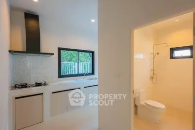 Modern kitchen with gas stove and adjacent bathroom in a bright, open layout home.