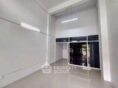 Spacious modern interior with high ceilings and sleek glass doors, perfect for versatile use.
