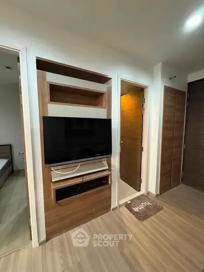 Modern living room with built-in TV unit and wooden flooring in a stylish apartment.