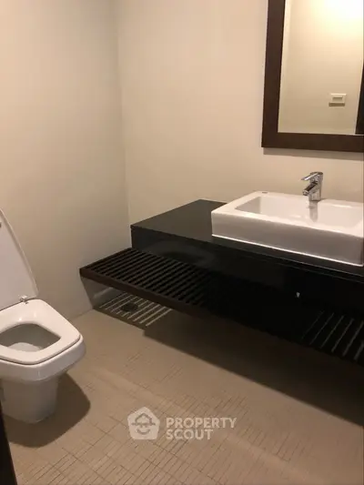 Modern bathroom with sleek sink and toilet in minimalist design.