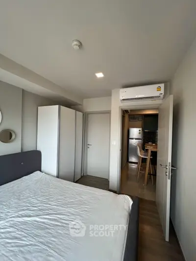 Modern bedroom with sleek design and view into a compact kitchen area