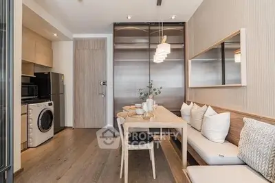 Modern compact kitchen with integrated appliances and cozy dining area, featuring wooden floors and stylish lighting.