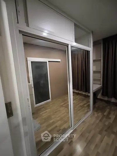 Modern bedroom with mirrored sliding closet doors and wooden flooring.