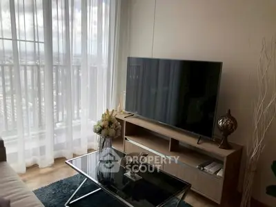 Modern living room with large TV and city view through sheer curtains.