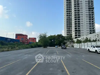 Spacious outdoor parking area adjacent to a modern high-rise residential building, offering ample parking spaces and easy access to urban amenities.
