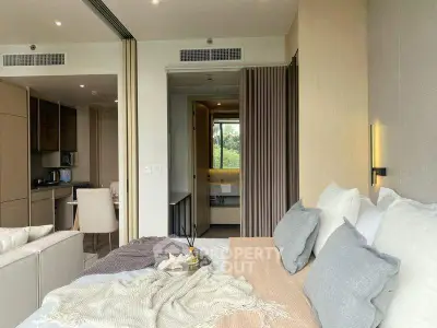 Modern studio apartment with cozy bedroom and open kitchen layout, featuring elegant decor and natural light.