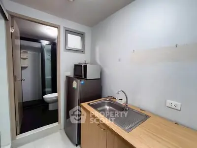 Compact kitchen with fridge and sink adjacent to bathroom