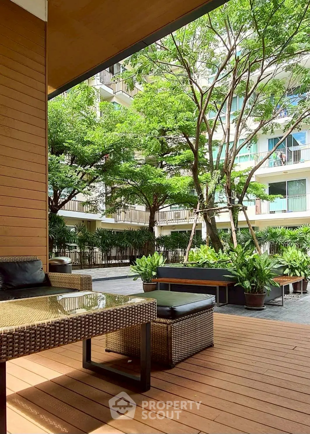 Charming outdoor patio with modern furniture and lush garden view in a contemporary apartment complex.
