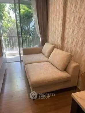 Cozy living room with a comfortable sofa and balcony view, perfect for relaxation.