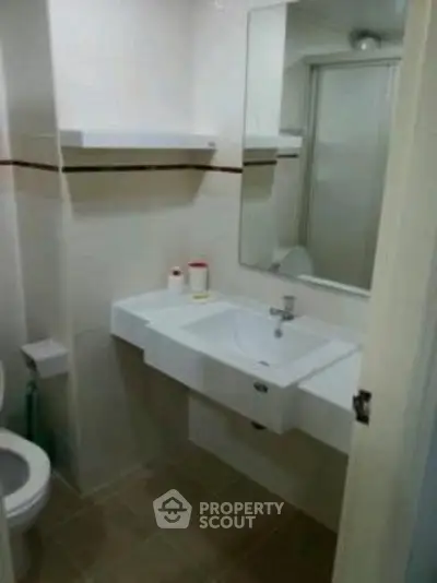 Compact bathroom with modern sink and mirror, featuring a clean and minimalist design.