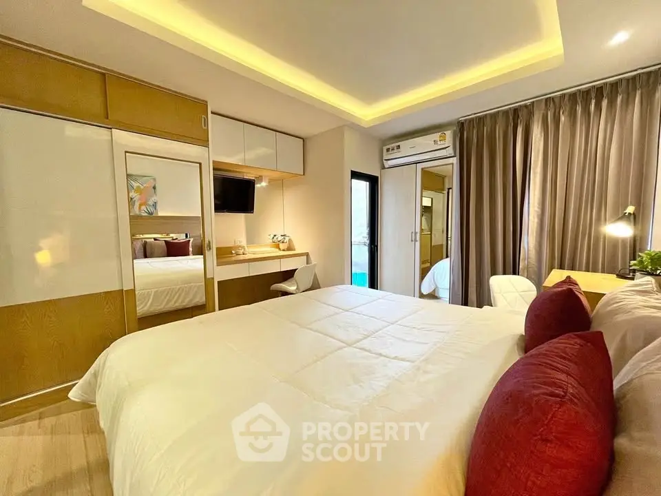 Modern bedroom with cozy lighting and stylish decor, featuring a built-in wardrobe and workspace.