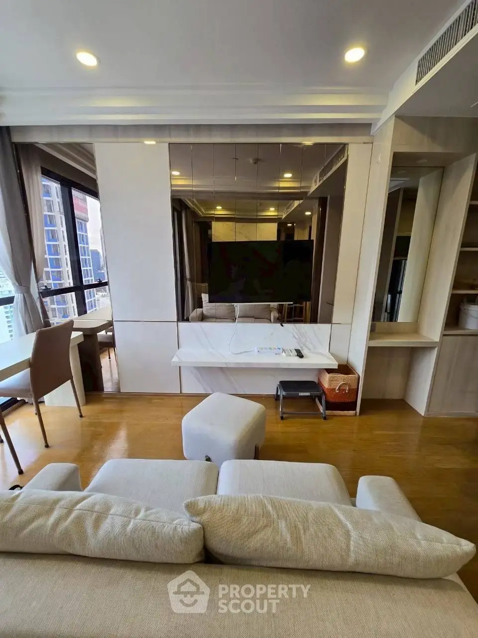 Modern living room with stylish furniture and city view, featuring a cozy sofa and dining area.