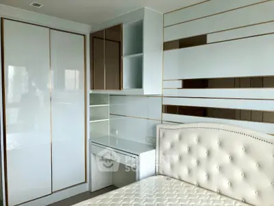 Modern bedroom with stylish white and brown decor, featuring built-in shelves and a plush headboard.