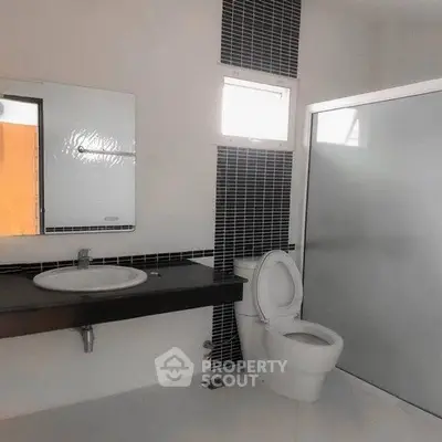 Modern bathroom with sleek black and white design, featuring a spacious shower and elegant fixtures.