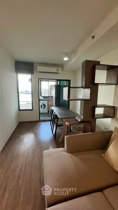 Modern living room with wooden flooring and balcony view, featuring a cozy sofa and stylish shelving.