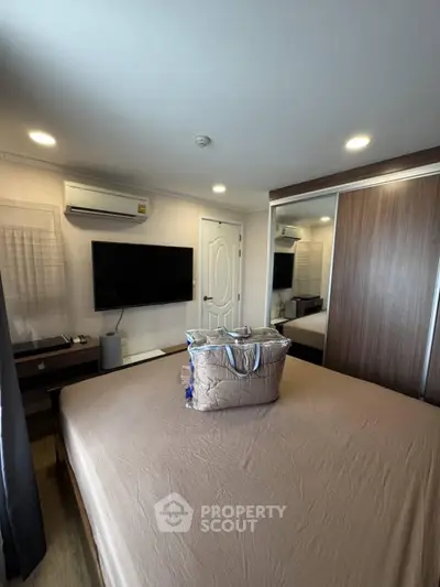 Modern bedroom with large bed, wall-mounted TV, and mirrored wardrobe